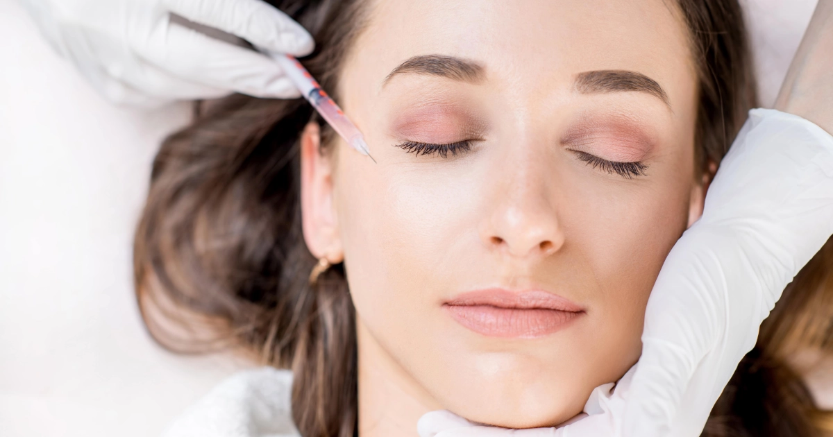 Woman receiving a cosmetic injection near the eye area, representing Botox or Dysport treatment for wrinkle reduction and facial rejuvenation in Lee’s Summit, MO.